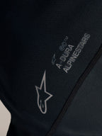 Schwarzes Stella A-Dura Ride Trikot, Detail des weißen Alpinestars-Logos und A-Dura Brandings auf Jacquard-Stoff.
