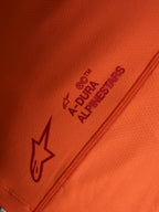 Oranges Stella A-Dura Ride Trikot-Detail mit Alpinestars Logo und A-DURA Schriftzug auf technischem Stretchgewebe.