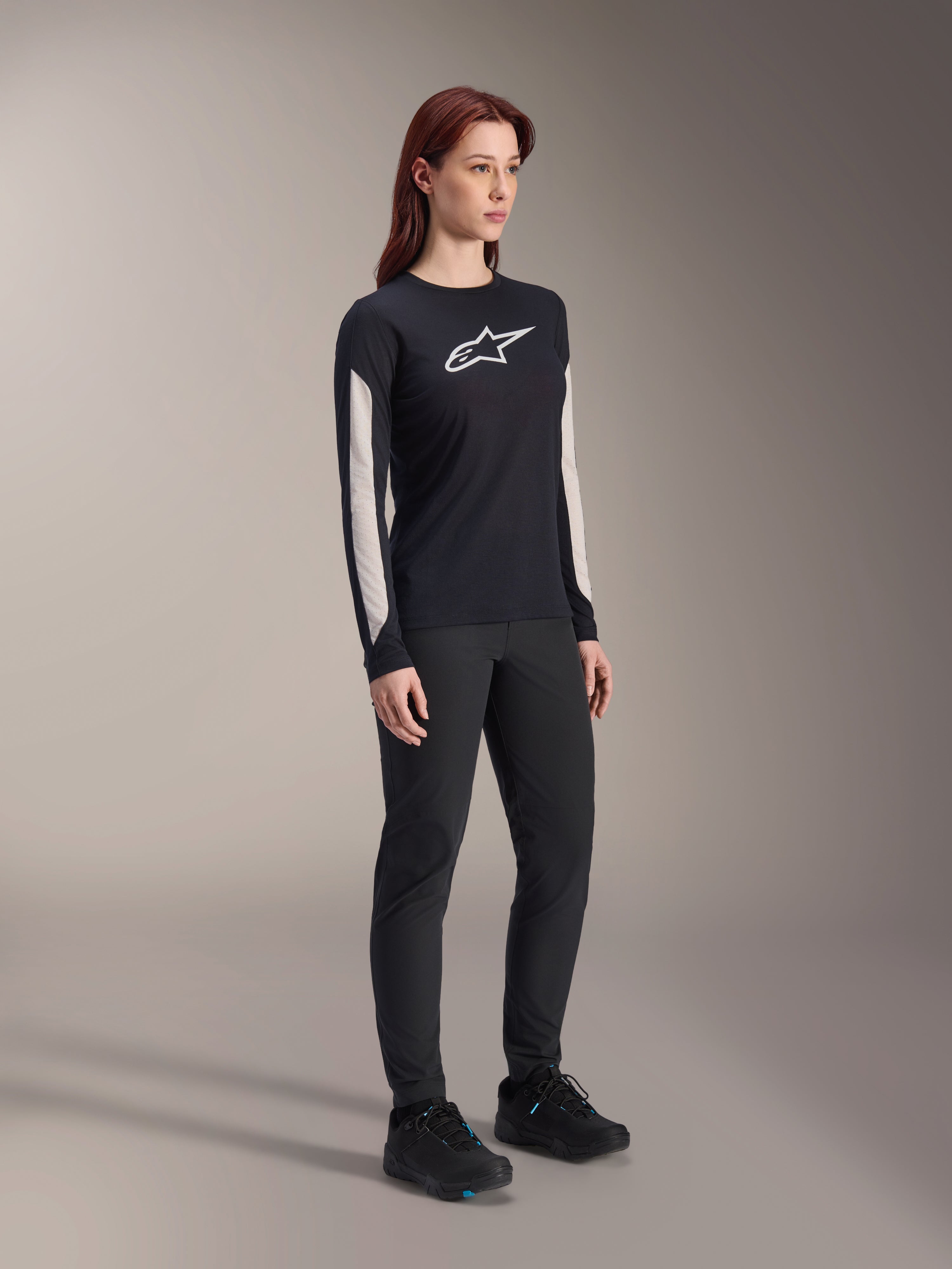 Alpinestars Women Stella A-Dura Dri Astar Long Sleeve Jersey, Black, featuring white mesh sleeve panels and white Astar logo, worn with black pants and shoes, technical cycling activewear for mountain biking