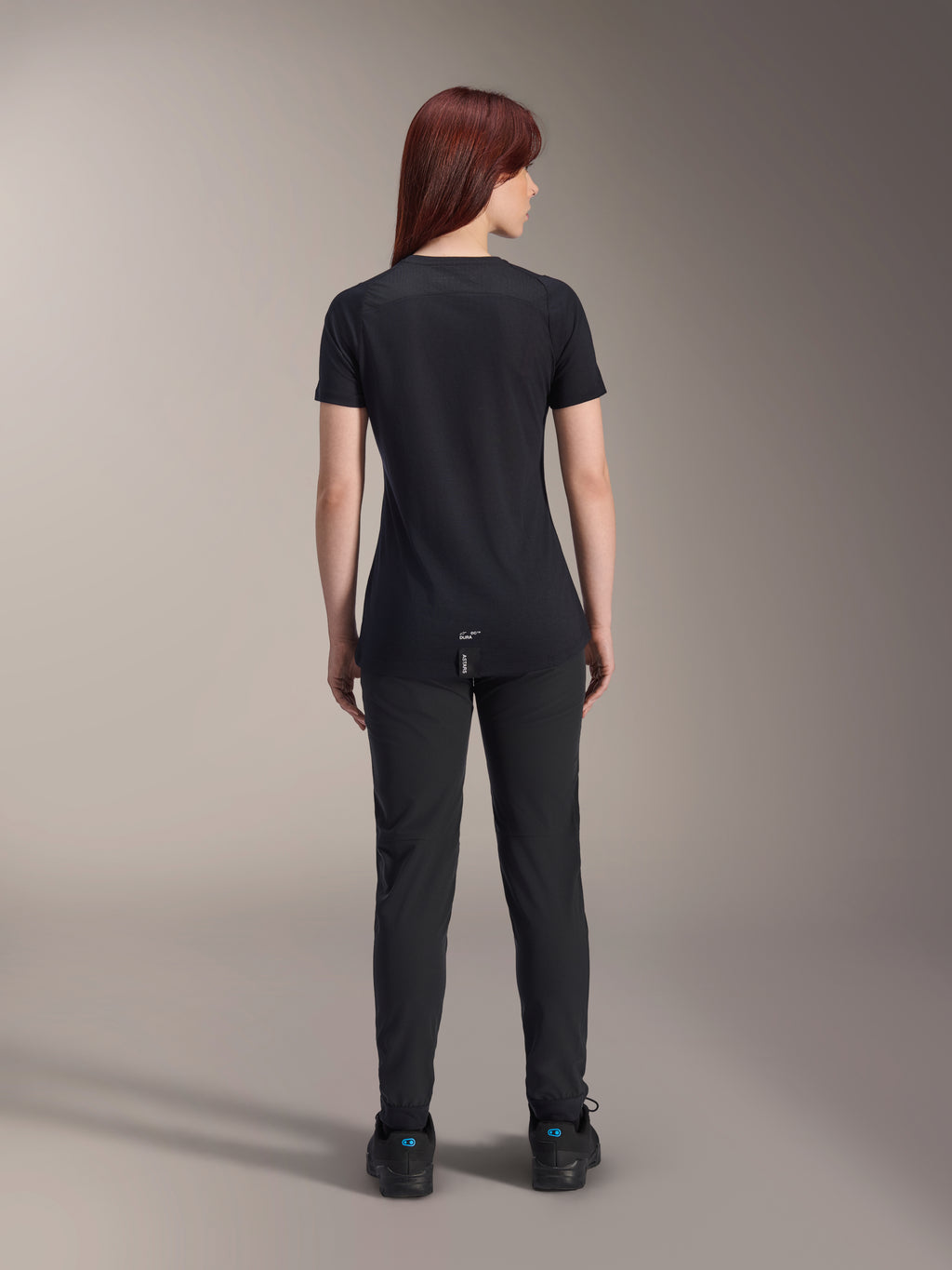 Alpinestars Women Stella A-Dura Dri Switch Short Sleeve Jersey, Black, rear view on a model, featuring a longer drop tail and technical mesh panels, paired with black pants, performance MTB cycling gear