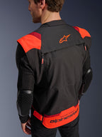 Alpinestars T-Stunt Air Jacket, Black Red Fluo and Dark Red, rear view on a model, showing mesh sleeves with honeycomb-textured elbow protectors, Alpinestars star logo on the upper back, and bold lower back branding with 'RACING AHEAD' text, modular sport-cut design for motorcycle riding.
