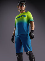 Alpinestars A-Dura Ride Shorts in Blau, Jersey mit limetten-blauem Farbverlauf und MTB-Schutzausrüstung.