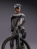 Graues Alpinestars A-Dura Race Langarmtrikot an einem MTB-Fahrer, mit schwarzen Akzenten und Profi-Radausrüstung.