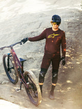 Bordeaux Alpinestars A-Dura Ride Long Sleeve Jersey with yellow logo, worn by a rider on a rocky mountain bike trail.