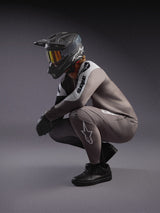Faded gray A-Supra Elite MTB jersey and matching pants, styled with a black full-face helmet and goggles for racing.