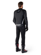 Alpinestars Missile V3 Lederjacke, Schwarz und Weiß, Rückansicht am Fahrer, mit markantem weißem Alpinestars-Schriftzug am unteren Rücken und kleinem Logo am oberen Rücken, getragen mit schwarzer Hose und Rennstiefeln, hochwertige Lederkonstruktion für Motorradrennen