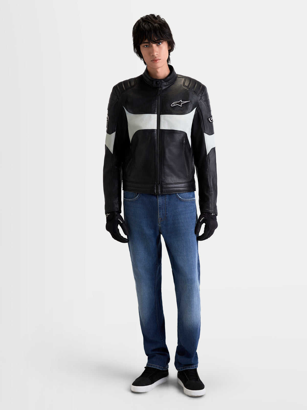 Alpinestars Revern Lederjacke, Herren-Urban-Motorradlederjacke in Schwarz und Metallgrau, Frontansicht an einem Model in Jeans und schwarzen Handschuhen, die den Heritage-Stil und die Vollnarbenleder-Konstruktion zeigt