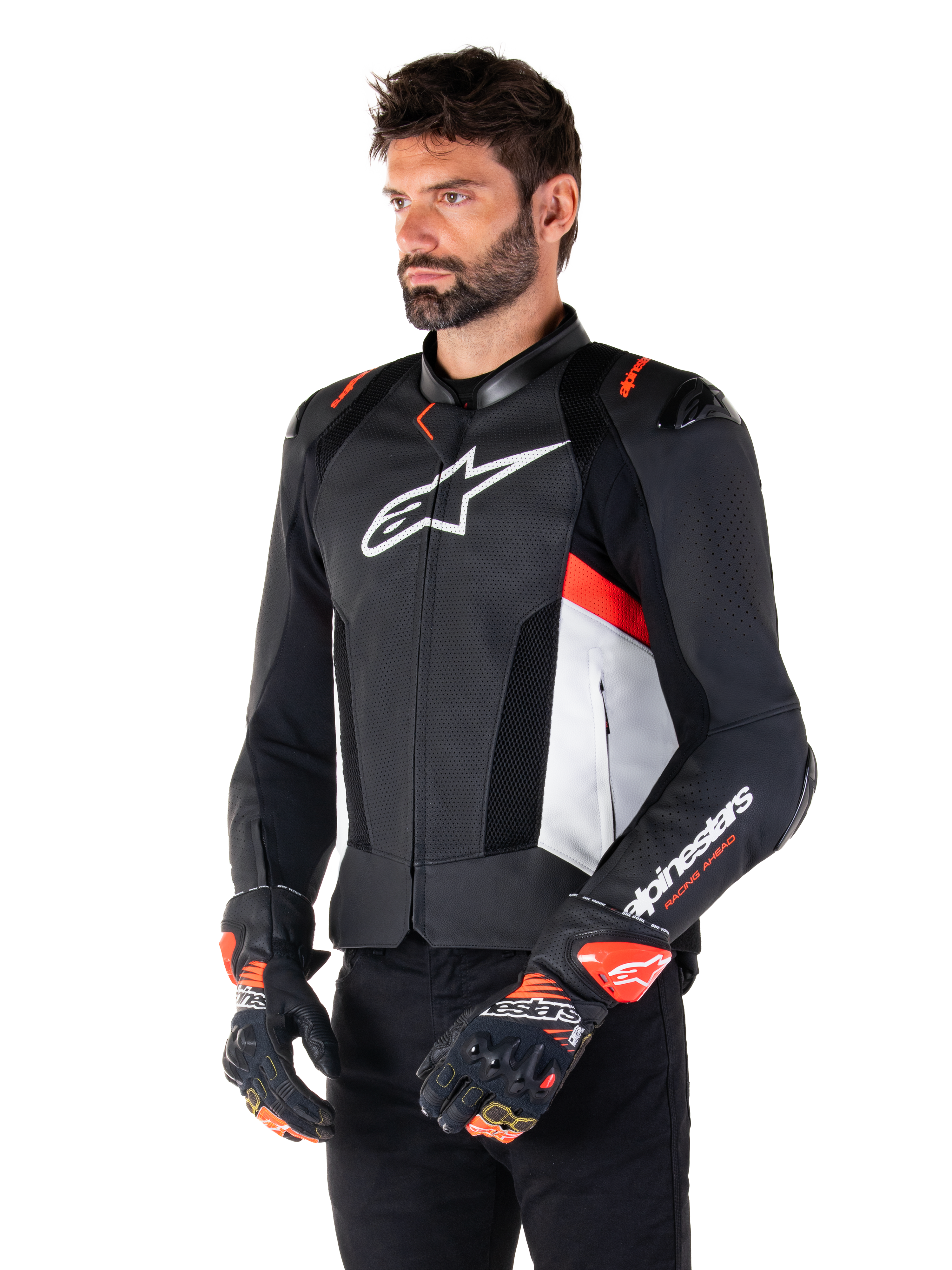 Alpinestars Missile V3 Airflow Lederjacke, Schwarz, Weiß und Fluo-Rot, Rennsport-Motorradjacke, getragen von einem Model mit passenden Handschuhen, mit perforierten Lederpanels, großem weißen Brust-Logo und schwarzen Schulterschleifern.