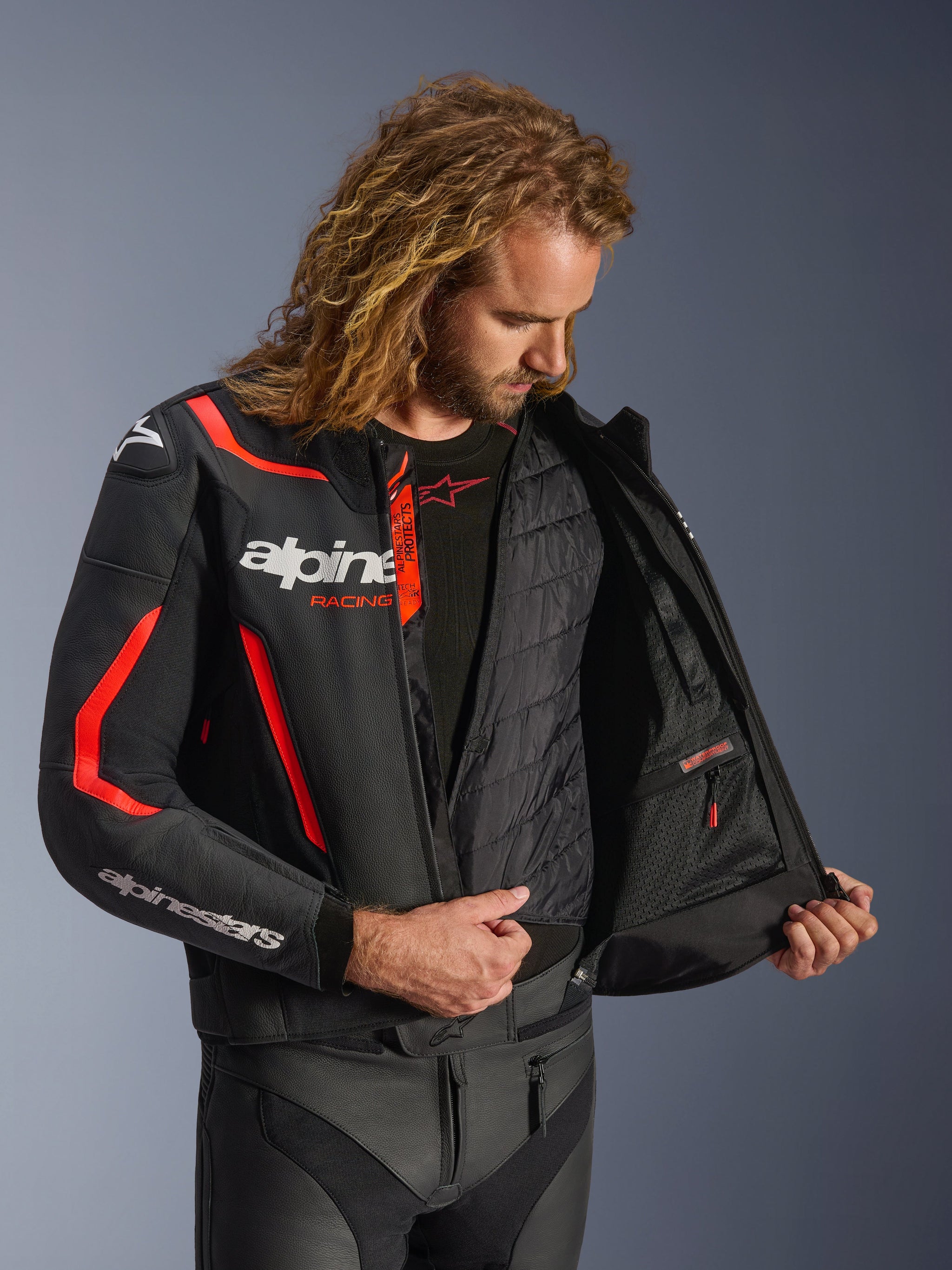 Alpinestars GP Force V2 Lederjacke in Schwarz und Rot Fluo, detaillierte Innenansicht am Modell, zeigt die herausnehmbare Thermoweste und die wasserdichte Innentasche, hochwertige Lederkonstruktion für Schutz beim sportlichen Fahren.