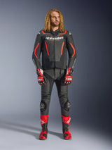 Männliches Model in der Alpinestars GP Force V2 Lederjacke in Schwarz und Rot Fluo, kombiniert mit passender Lederhose, roten Rennhandschuhen und roten Performance-Stiefeln, professionelle Motorrad-Sportbekleidung