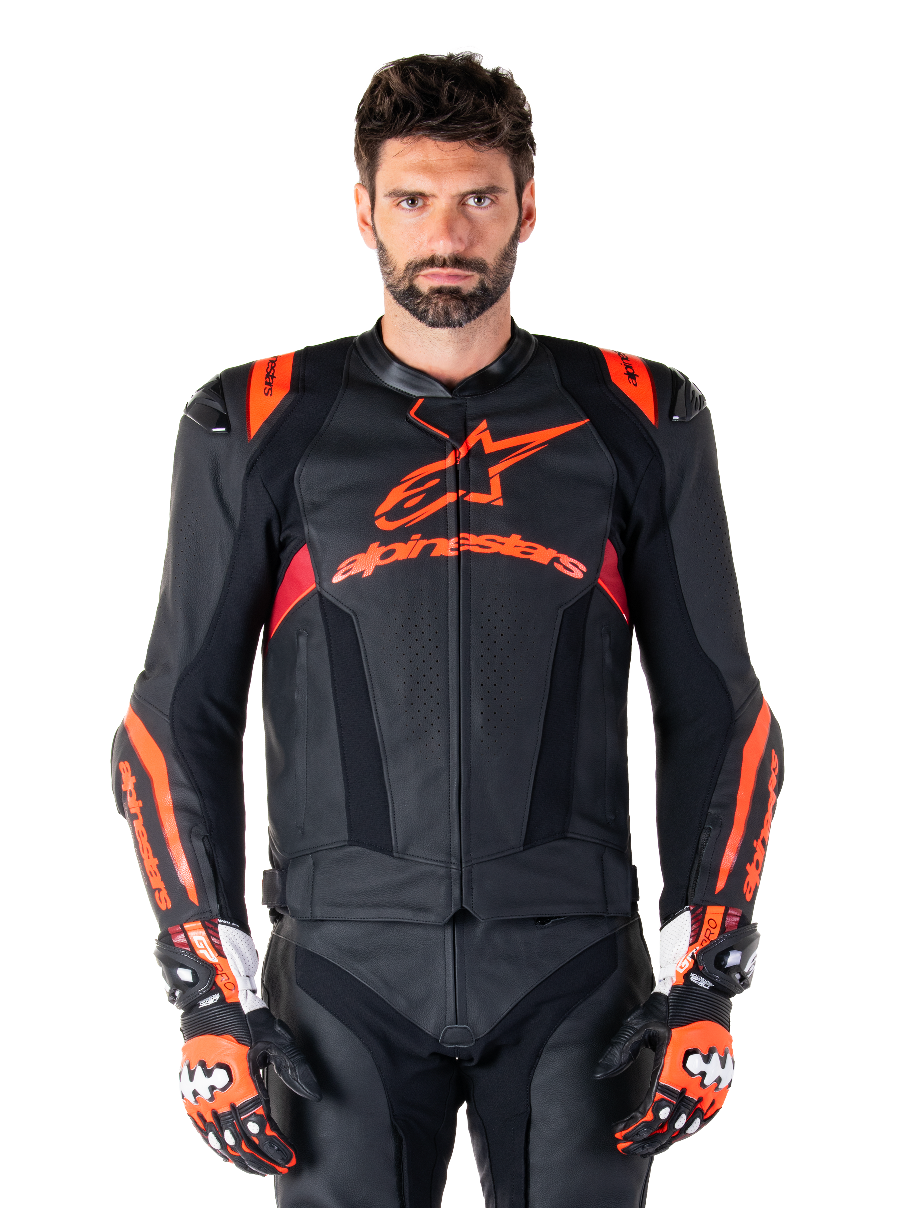 Alpinestars Missile V3 Ignition Lederjacke, Motorrad-Rennjacke, Schwarz und Fluo-Rot, getragen mit passenden Rennhandschuhen und Lederhose, mit perforierter Belüftung und markantem Alpinestars-Branding, professionelle Rennausrüstung