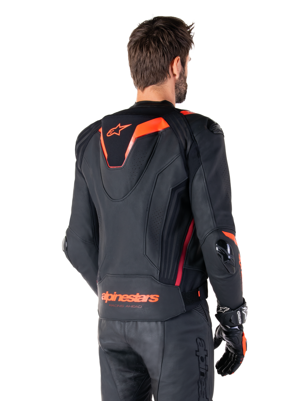 Alpinestars Missile V3 Ignition Lederjacke, Herren-Rennsportjacke, Schwarz mit Red Fluo Akzenten, Rückansicht mit schmalem aerodynamischem Sport-Höcker und Alpinestars-Logo am unteren Rücken, getragen mit schwarzer Lederhose und Rennsport-Handschuhen, schlankes professionelles Motorsport-Design