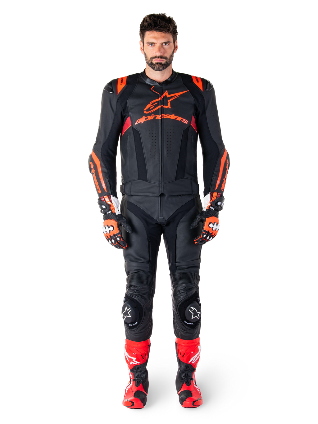 Männliches Model in der Alpinestars Missile V3 Ignition Lederjacke in Schwarz, Fluo-Rot und Dunkelrot, komplette Motorrad-Rennausrüstung mit passender Lederhose, Rennhandschuhen und Stiefeln, markantes Alpinestars-Branding auf der Brust, nach vorne gerichtete Pose, professionelles Sport-Fahrer-Outfit
