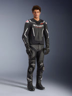 Alpinestars GP Force V2 Air Leather Jacket in Black and White, worn by a male rider with matching black racing pants, gloves, and boots, featuring perforated leather panels, white accents, and red Alpinestars logo on the chest, sport motorcycle riding gear