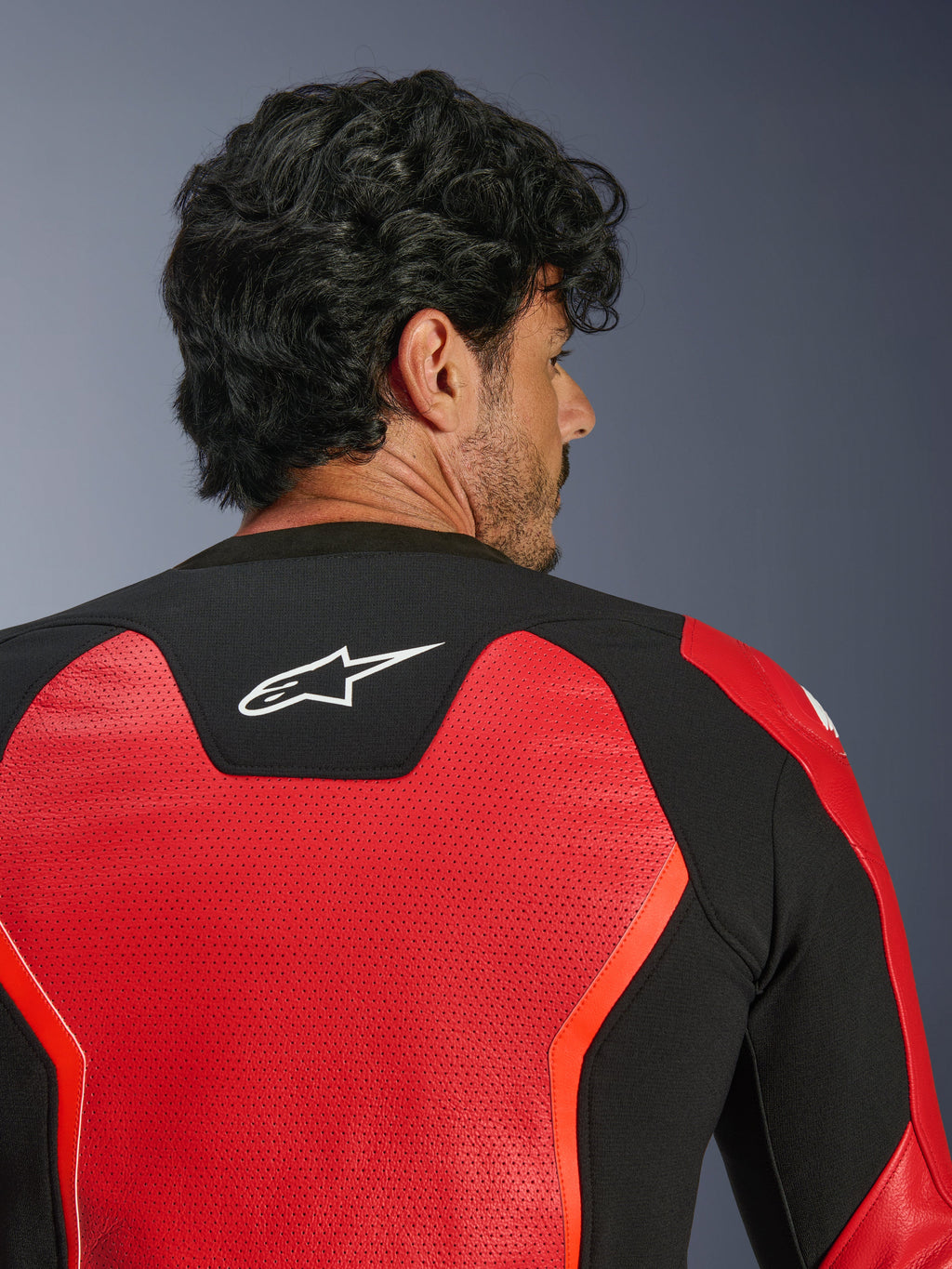 Alpinestars GP Force V2 Air Leather Jacket, Red and Black, close-up back view featuring extensive perforated leather for airflow, black stretch panel with white Astars logo, sport-fit motorcycle riding jacket