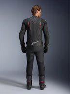 Alpinestars Dusk Airflow Leather Jacket, Black and Red Fluo, rear view showing extensive perforations and large white logo on the lower back, worn with matching leather racing gear including pants, boots, and gloves