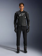 Alpinestars Dusk Airflow Lederjacke, Schwarz und Weiß, Motorrad-Lederjacke mit perforierten Paneelen für Luftzirkulation, weißes Astars-Logo auf der Brust, getragen von einem männlichen Fahrer mit schwarzer Hose, Handschuhen und Motorradstiefeln, professionelle Studioaufnahme für Sport-Motorradbekleidung.