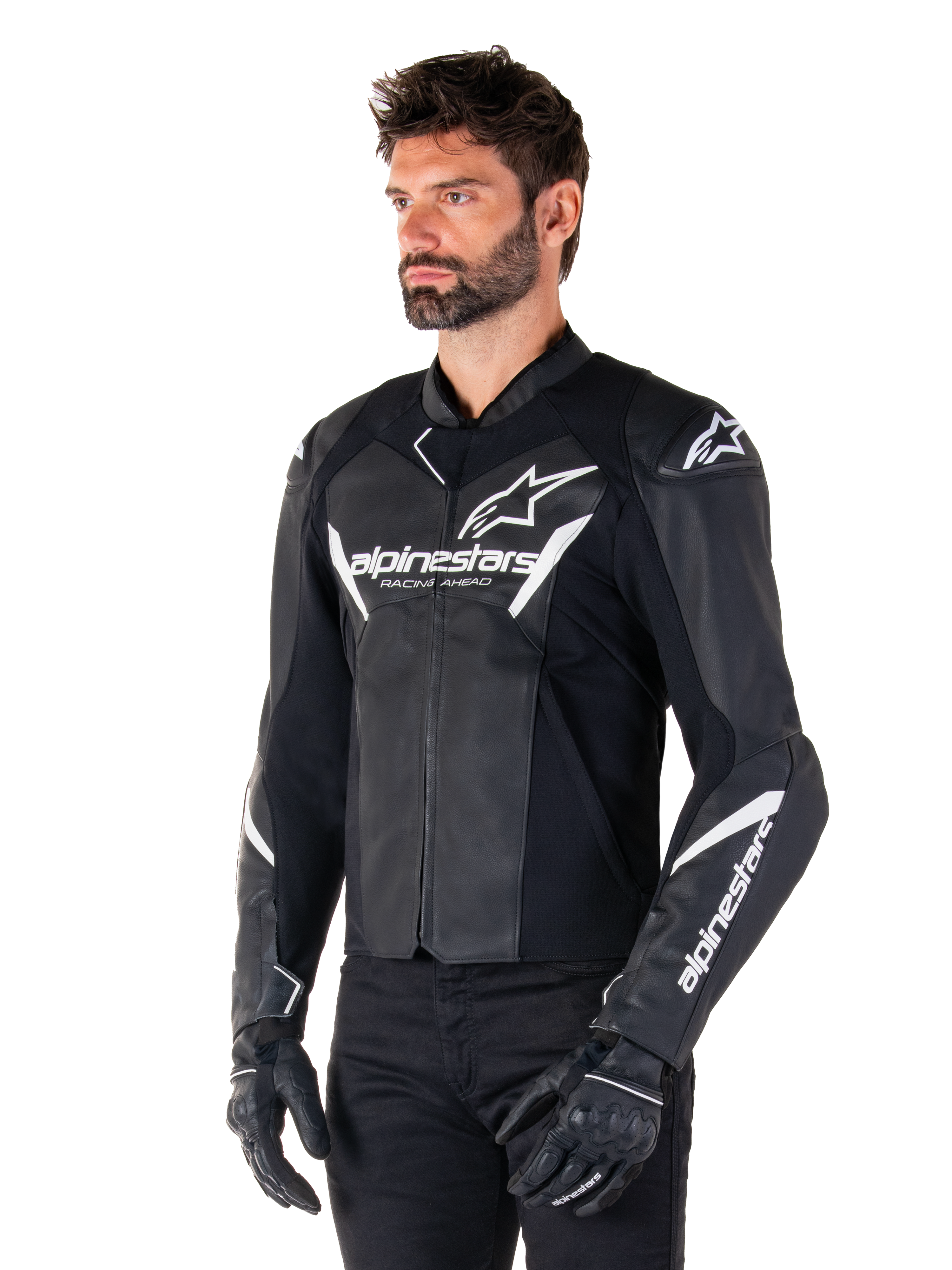 Alpinestars Faster V3 Lederjacke, Sport-Motorradjacke, Schwarz und Weiß, auffälliges weißes Alpinestars-Logo und 'Racing Ahead'-Schriftzug auf der Brust, Stern-Logos auf den Schultern, hochwertige Lederkonstruktion mit Stretcheinsätzen, getragen von einem Modell mit schwarzer Hose und Handschuhen