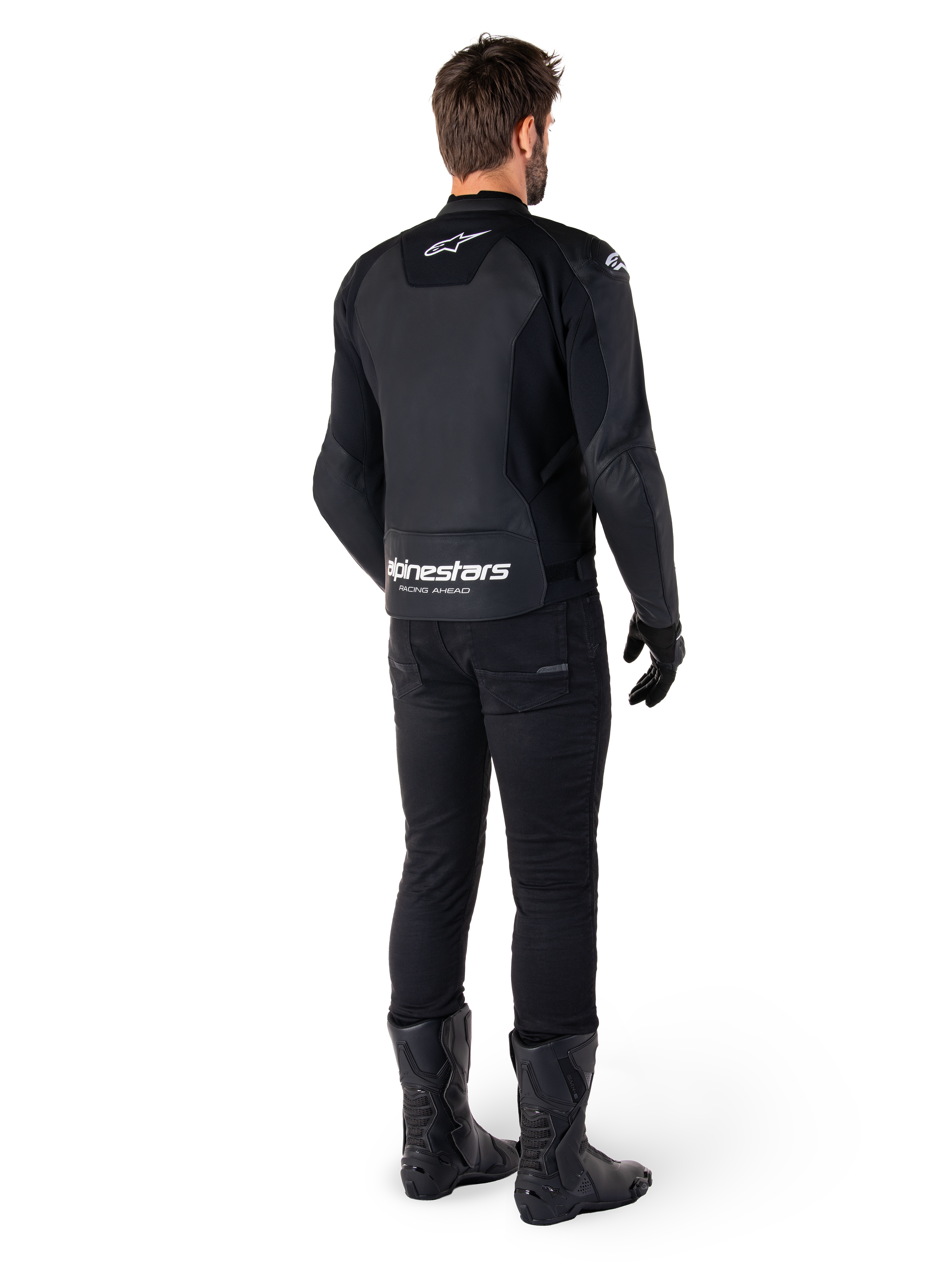 Alpinestars Faster V3 Lederjacke, Rückansicht, Schwarz und Weiß, mit „alpinestars RACING AHEAD“-Branding am unteren Rücken, getragen mit schwarzer Motorradhose und Stiefeln, sportlich inspirierte Motorrad-Lederjacke mit Stretcheinsätzen.