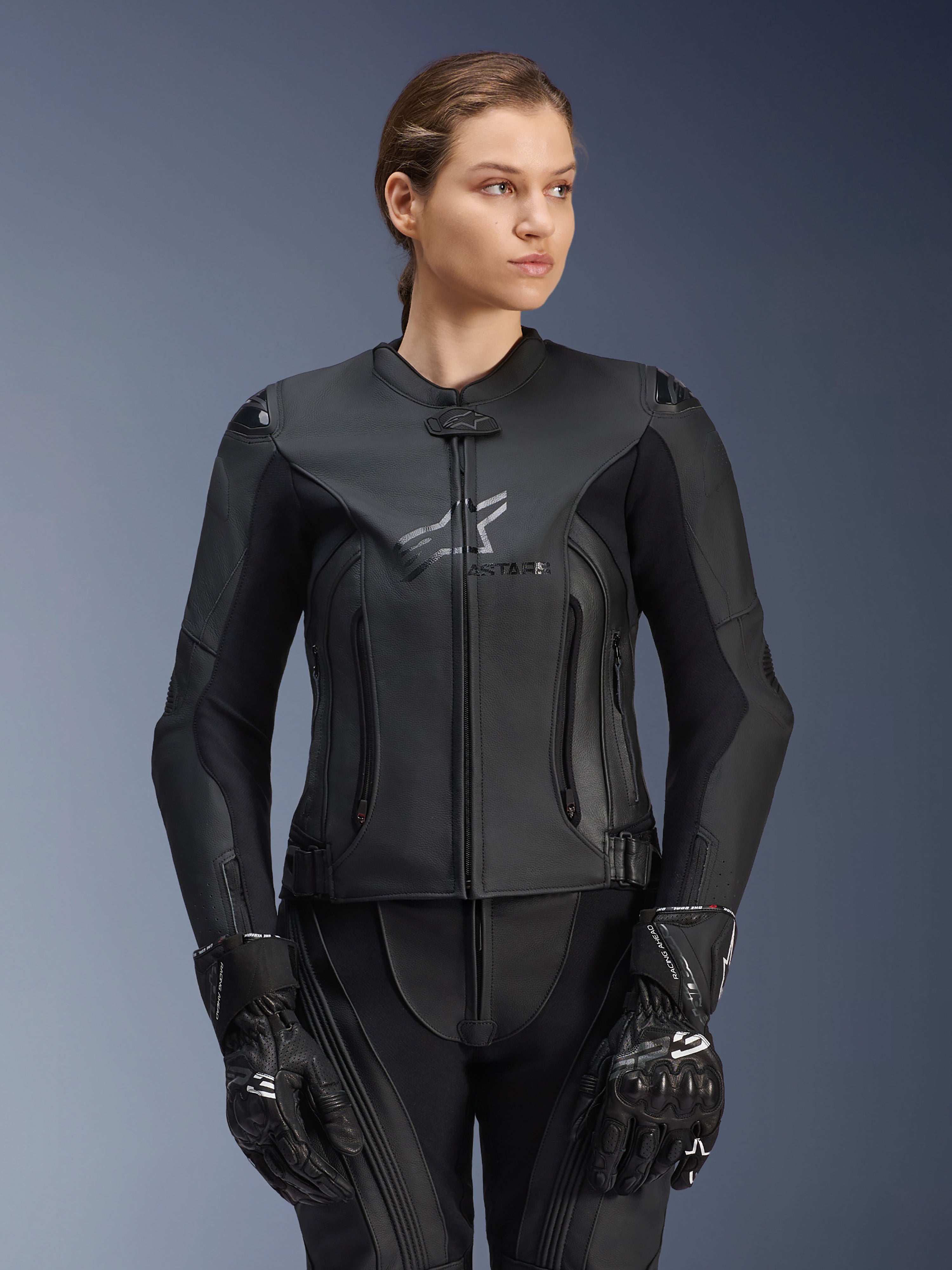 Alpinestars Stella GP Plus V4 Lederjacke, Schwarz, Damen-Motorrad-Rennjacke, hochwertige Lederkonstruktion mit Schutzpolsterung, elegantes Design mit dezentem Logo, getragen von einem weiblichen Model mit passender schwarzer Ausrüstung