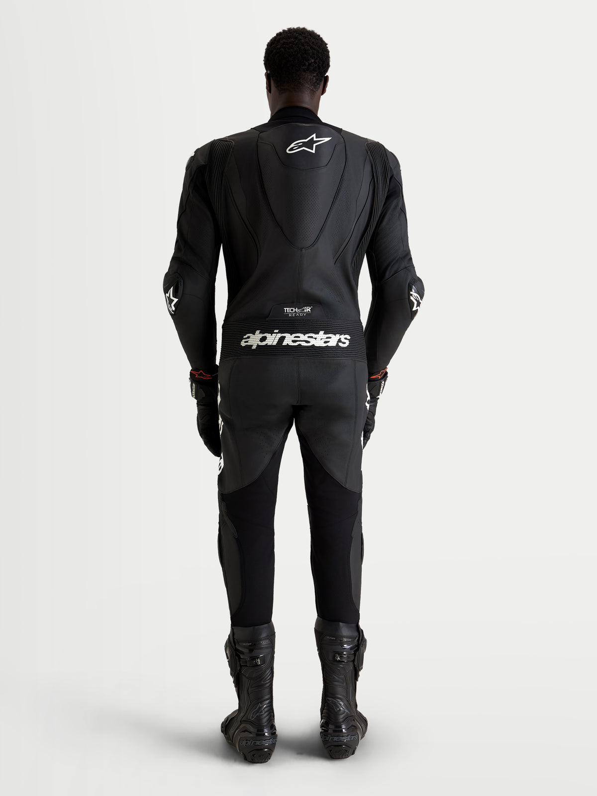 Alpinestars Missile V3 Leather Suit - 1 Piece, men's motorcycle racing suit, black leather with white logos and aerodynamic speed hump, rear view of a rider