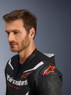 Alpinestars GP Force V2 Leather Suit 2-Piece, Close-up of jacket worn by male model, Black White and Red Fluo, featuring perforated leather, red star logo on the shoulder, aerodynamic speed hump, and Alpinestars branding on the chest, professional motorcycle racing gear
