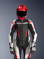Female rider wearing Alpinestars Stella GP-R7 2-Piece Leather Suit, Black White and Red Fluo colors, featuring perforated panels and 'Racing Ahead' branding, worn with a red helmet and white/black GP Pro gloves, professional racing gear setup