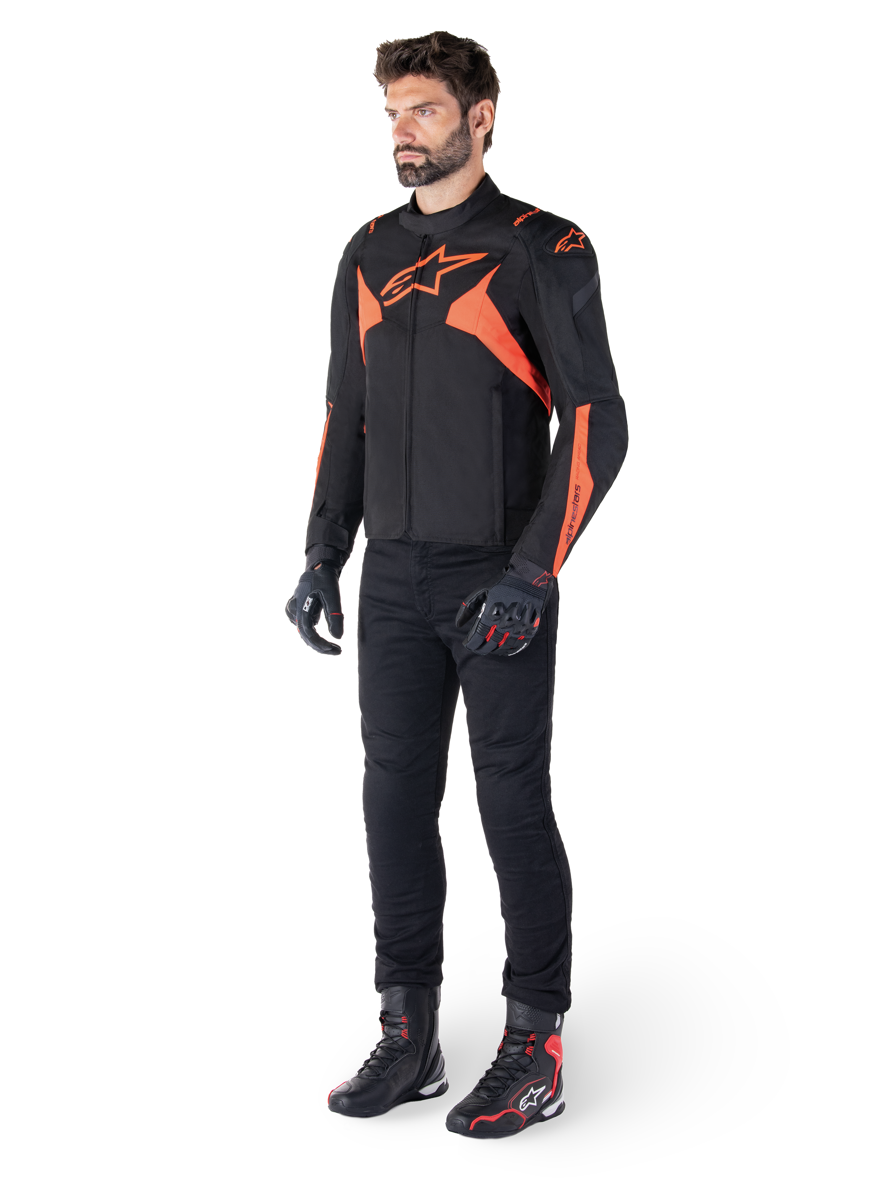 Alpinestars T-Jaws V4 Waterproof Jacket, Black and Red Fluo, worn by a male model with black pants, gloves, and boots, featuring bright orange accents and the Alpinestars logo, sporty design for motorcycle riding