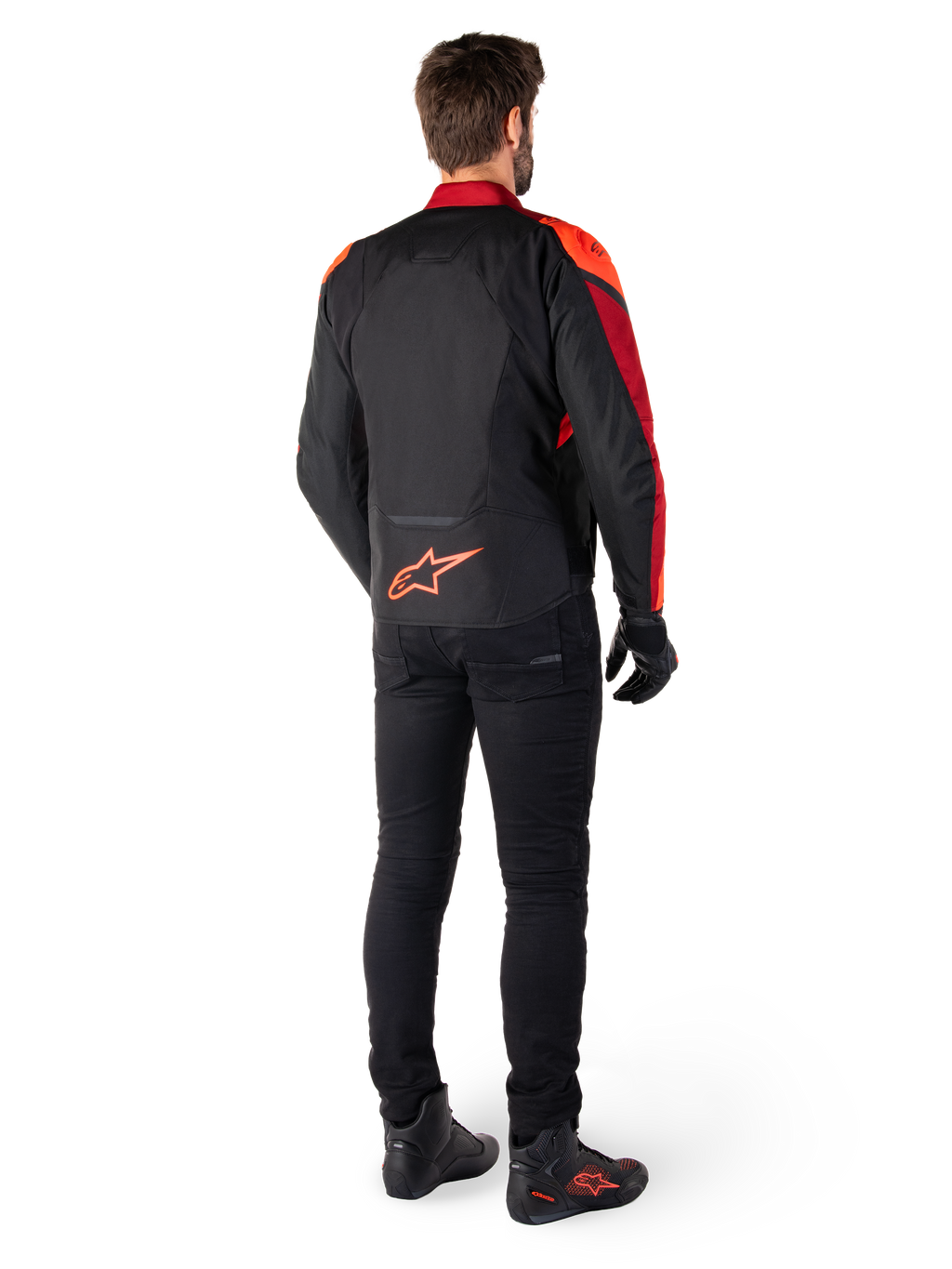 Alpinestars T-Jaws V4 Waterproof Jacket in Black Red Fluo Dark Red, rear view of a rider wearing the textile jacket with black pants and riding boots, featuring a bold red Alpinestars logo on the lower back.