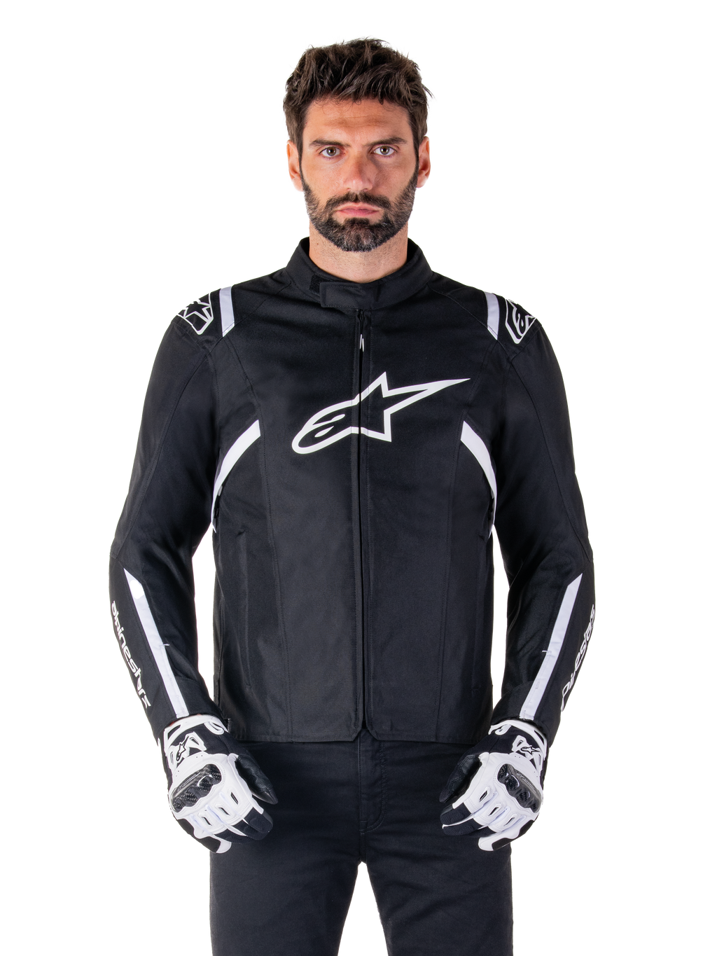 Alpinestars T-SPS V2 Waterproof Jacket in Schwarz und Weiß, Vorderansicht am Modell, wasserdichte Textil-Motorradjacke mit weißen Schulter- und Armstreifen, großes weißes Alpinestars-Logo auf der Brust, getragen mit Motorrad-Schutzhandschuhen, schlanke sportlich inspirierte Silhouette.