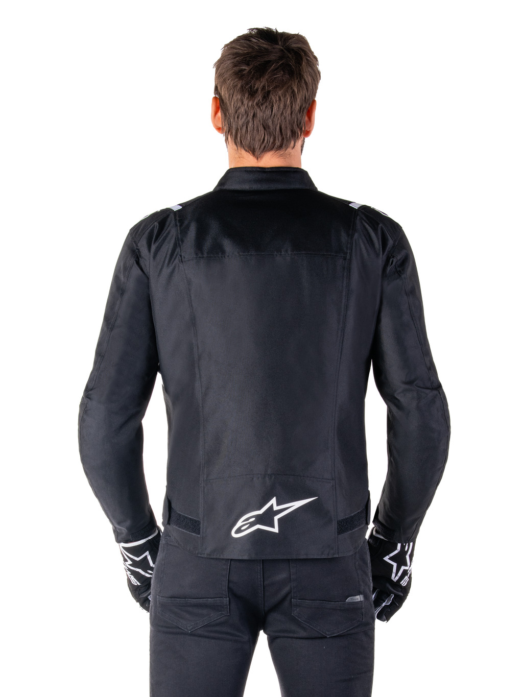 Alpinestars T-SPS V2 Wasserdichte Jacke, Schwarz und Weiß, Rückansicht mit weißem Alpinestars-Logo auf dem unteren Rücken, getragen mit schwarzer Hose und Handschuhen, sportlich geschnittene Textil-Motorradjacke