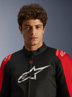 Male model wearing the Alpinestars T-SPS V2 Waterproof Jacket, Black with Red accents and white logo, close-up portrait view, textile sport motorcycle jacket
