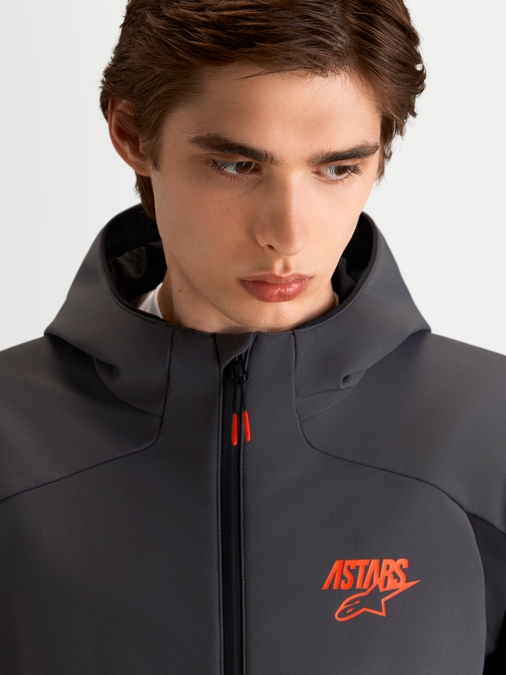 Alpinestars Aeroshell Wp Jacke, Herren-Motorradjacke in Schwarz und Dunkelgrau, Kapuze, Nahaufnahme des Modells mit orangem ASTARS-Logo