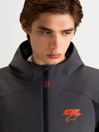 Alpinestars Aeroshell Wp Jacke, Herren-Motorradjacke in Schwarz und Dunkelgrau, Kapuze, Nahaufnahme des Modells mit orangem ASTARS-Logo