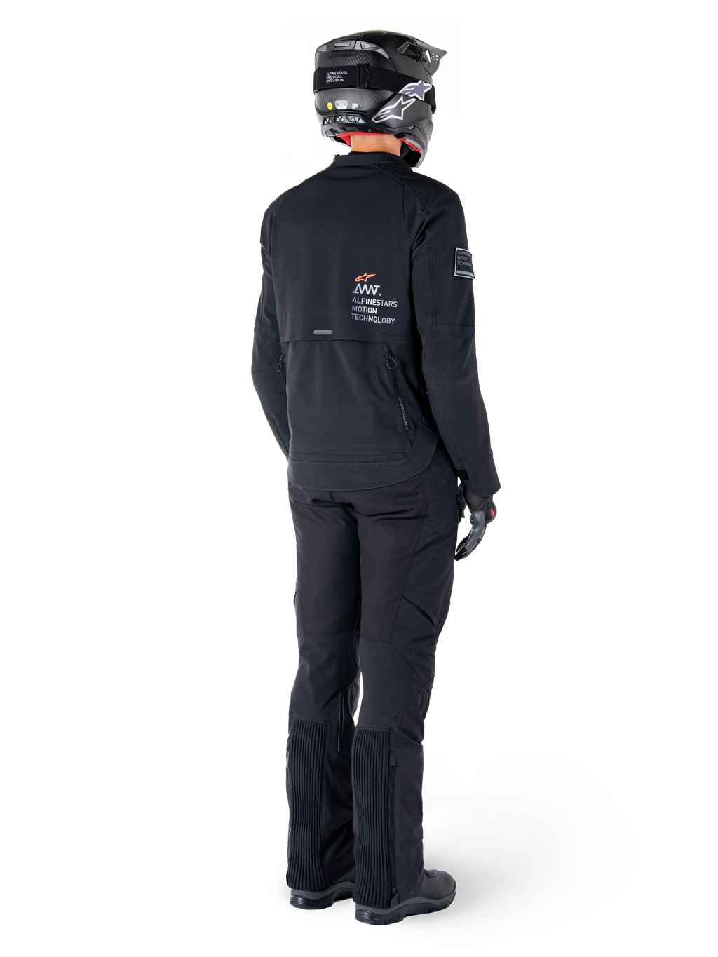 Alpinestars AMT-8 Stretch Drystar® XF Jacket, Black, rear view of a rider wearing the jacket with matching black pants and a black helmet, featuring 'Alpinestars Motion Technology' branding on the back, technical stretch material for adventure motorcycle riding