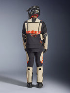 Alpinestars Halo Pro Drystar® XF Laminierte Jacke, Adventure-Motorradjacke, Mastic Black, Rückansicht eines Fahrers, der eine passende Hose und einen schwarzen Helm trägt, mit auffälligem orangefarbenem Alpinestars-Branding und modularen Belüftungspanelen für vielseitige Abenteuerfahrten.