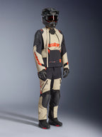 Alpinestars Halo Pro Drystar® XF Laminierte Jacke in Mastic Black, Adventure-Motorradjacke getragen mit passender Hose, Integralhelm, Handschuhen und Stiefeln, mit beigen und schwarzen Einsätzen und roten Logos, technisches Mehrjahreszeiten-Design.