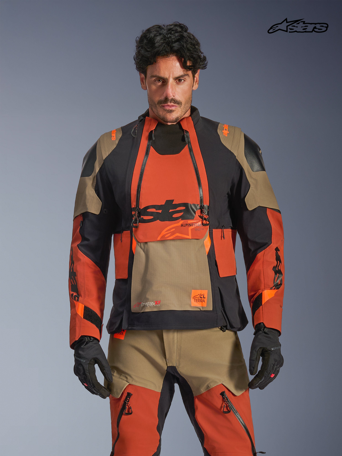 Alpinestars Harok Pro Drystar® XF Laminated Jacket, men's adventure touring motorcycle jacket in walnut, rust, and black, front view on a model wearing matching gear, featuring waterproof textile construction and modular ventilation panels.