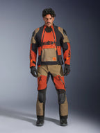 Male model wearing Alpinestars Halo Pro Drystar® XF Laminated Jacket and matching pants in Walnut Rust Black, modular adventure motorcycle gear featuring front ventilation panels and zippers, styled with black motorcycle gloves and boots.