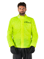 Alpinestars Hurricane Rain V2 Jacke, Motorrad-Regenjacke, Neongelb, getragen von einem Model mit schwarzer Hose und Handschuhen, hoher Kragen mit reflektierenden Laschen, vordere Sturmklappe mit Alpinestars-Logo, hochsichtbare wasserdichte Ausrüstung