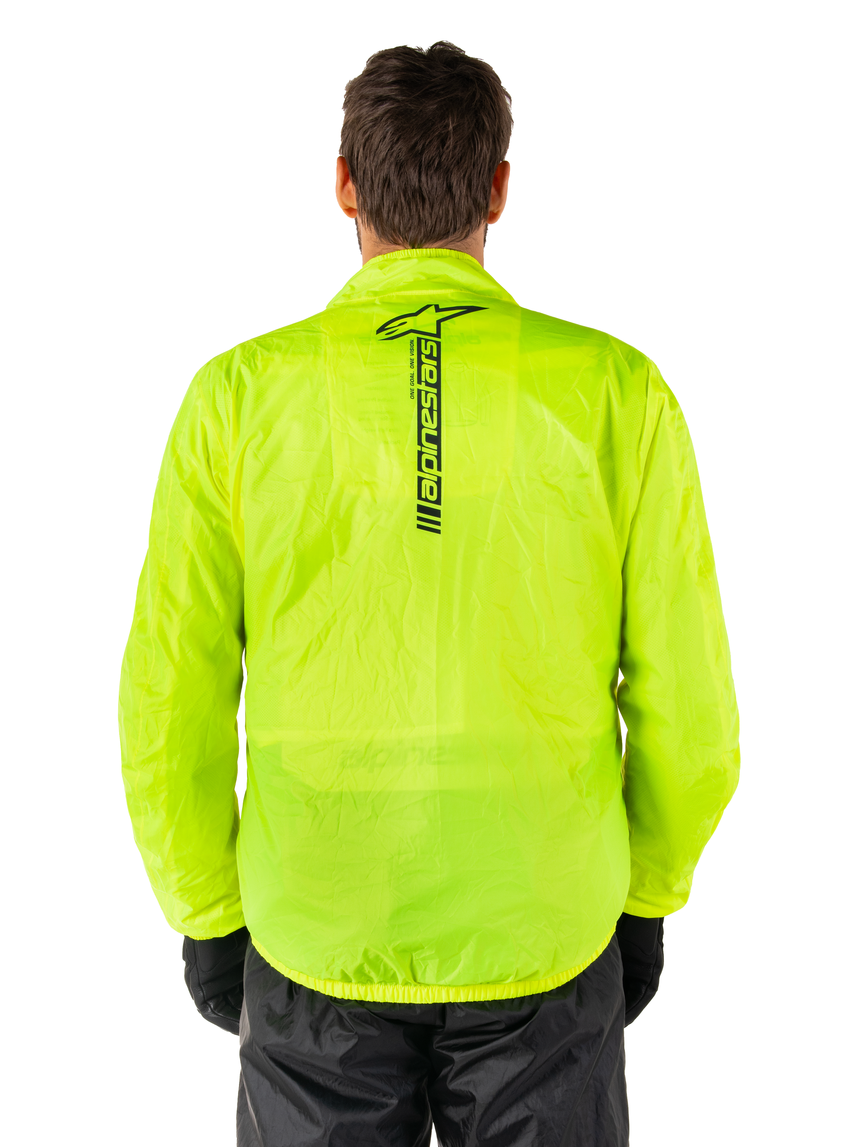 Alpinestars Hurricane Rain V2 Jacke, Motorrad-Regenjacke, Gelb Fluo, Rückansicht mit vertikalem schwarzem Alpinestars-Logo in der Rückenmitte, leichtes wasserdichtes Material, getragen mit schwarzer Fahrhose und Handschuhen