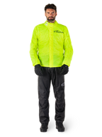 Alpinestars Hurricane Rain V2 Jacke und Hose, Neongelb und Schwarz, wasserdichte Motorrad-Regenkombi, getragen mit schwarzen Handschuhen und Stiefeln, Alpinestars-Logo auf der Brust und am Bein