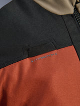 Close-up detail of the Alpinestars Andes V4 Drystar® Jacket in Walnut Rust Black, highlighting the integrated chest hydration hose loop and durable ripstop textile construction.