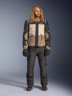 Alpinestars Andes V4 Drystar® Jacket, Walnut Mastic Black, worn with black motorcycle pants and gloves, featuring a multi-panel adventure design with orange accents and Alpinestars branding, technical textile gear for all-weather riding