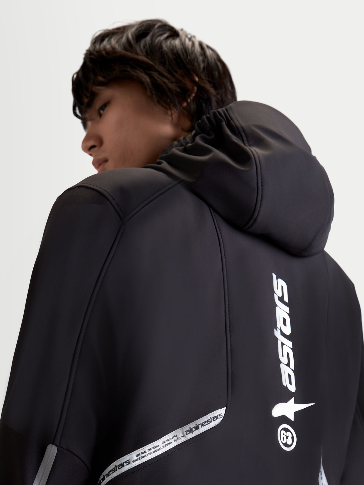 Alpinestars C 5 Drystar Jacke, urbane Herren-Motorradjacke aus Textil in Schwarz, Rückansicht mit integrierter Kapuze und reflektierenden Branding-Details, getragen von einem Model