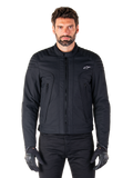 Alpinestars Clayton WR Jacke, schwarze Motorradjacke, von einem Model getragen, mit gesteppten Schulterdetails und technischen Grafiken, zentraler Vislon-Reißverschluss, vertikale Reißverschlusstaschen, kleines weißes Logo auf der Brust, urbane Fahrerausrüstung für den Straßengebrauch