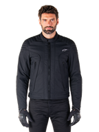 Alpinestars Clayton WR Jacke, schwarze Motorradjacke, von einem Model getragen, mit gesteppten Schulterdetails und technischen Grafiken, zentraler Vislon-Reißverschluss, vertikale Reißverschlusstaschen, kleines weißes Logo auf der Brust, urbane Fahrerausrüstung für den Straßengebrauch