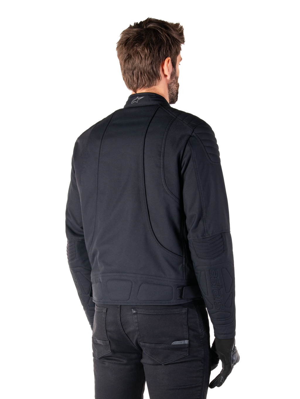 Alpinestars Clayton WR Jacke in Schwarz, Rückansicht in Dreiviertel-Perspektive an einem männlichen Model, urbane Motorradjacke mit gesteppten Polsterungen an Schultern und Ellbogen, technischen Stepplinien und reflektierendem Logo am Kragen, kombiniert mit schwarzer Hose und Handschuhen.