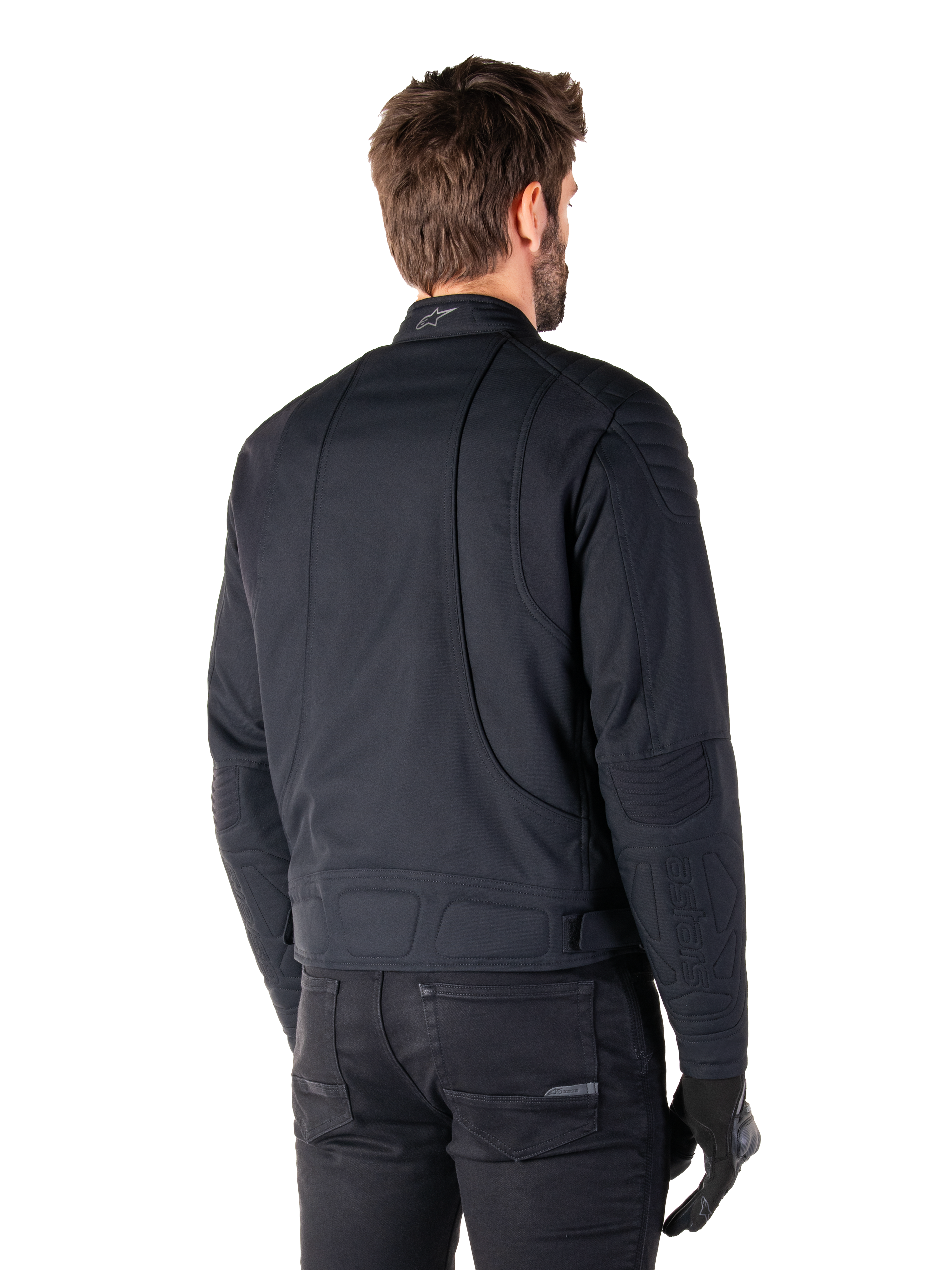 Alpinestars Clayton WR Jacke in Schwarz, Rückansicht in Dreiviertel-Perspektive an einem männlichen Model, urbane Motorradjacke mit gesteppten Polsterungen an Schultern und Ellbogen, technischen Stepplinien und reflektierendem Logo am Kragen, kombiniert mit schwarzer Hose und Handschuhen.