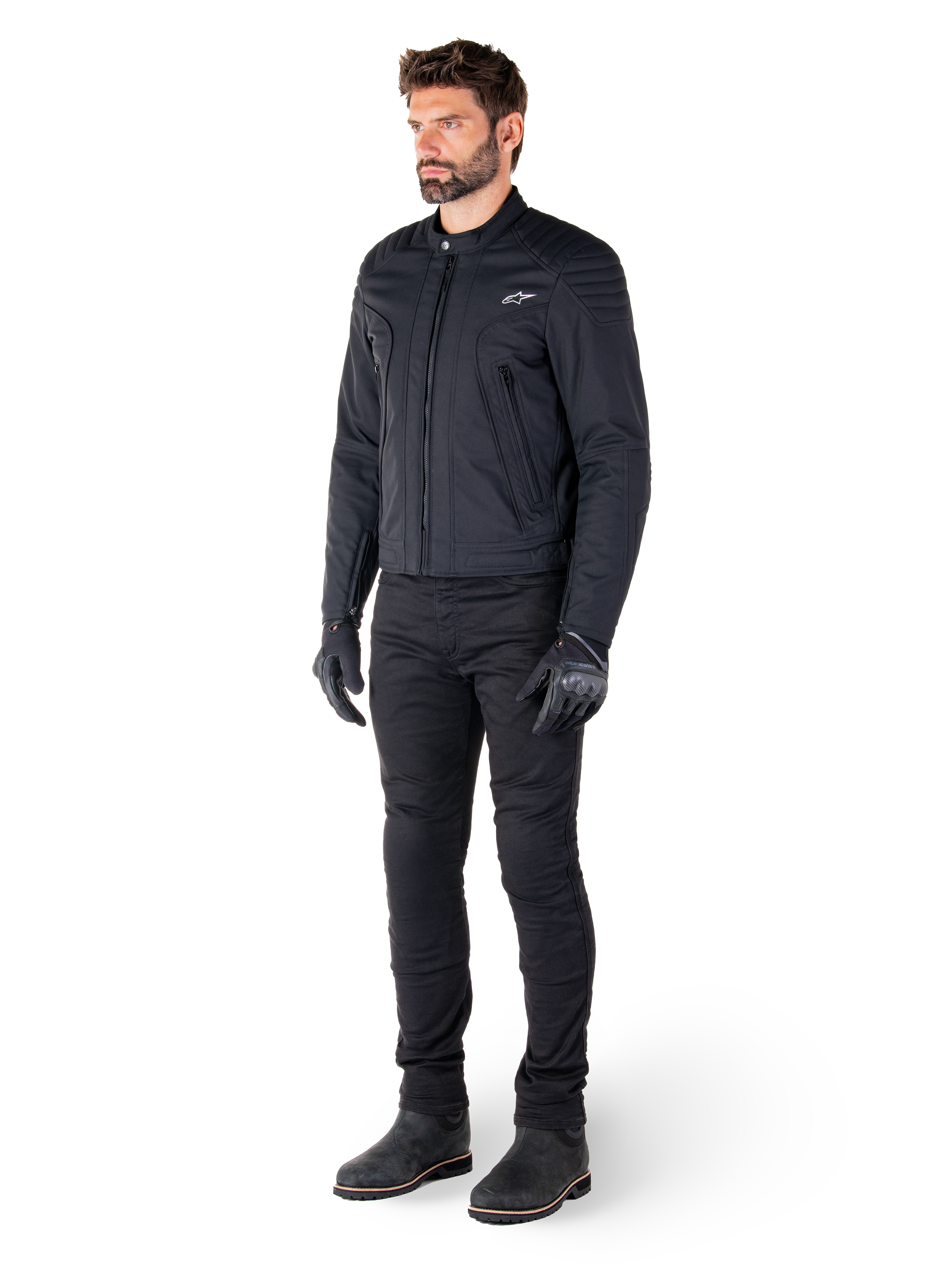 Männlicher Fahrer in der Alpinestars Clayton WR Jacke, schwarze Urban-Motorradjacke, Slim-Fit-Design mit gesteppten Schulterakzenten und mattem Finish, kombiniert mit schwarzer technischer Motorradhose und Handschuhen.